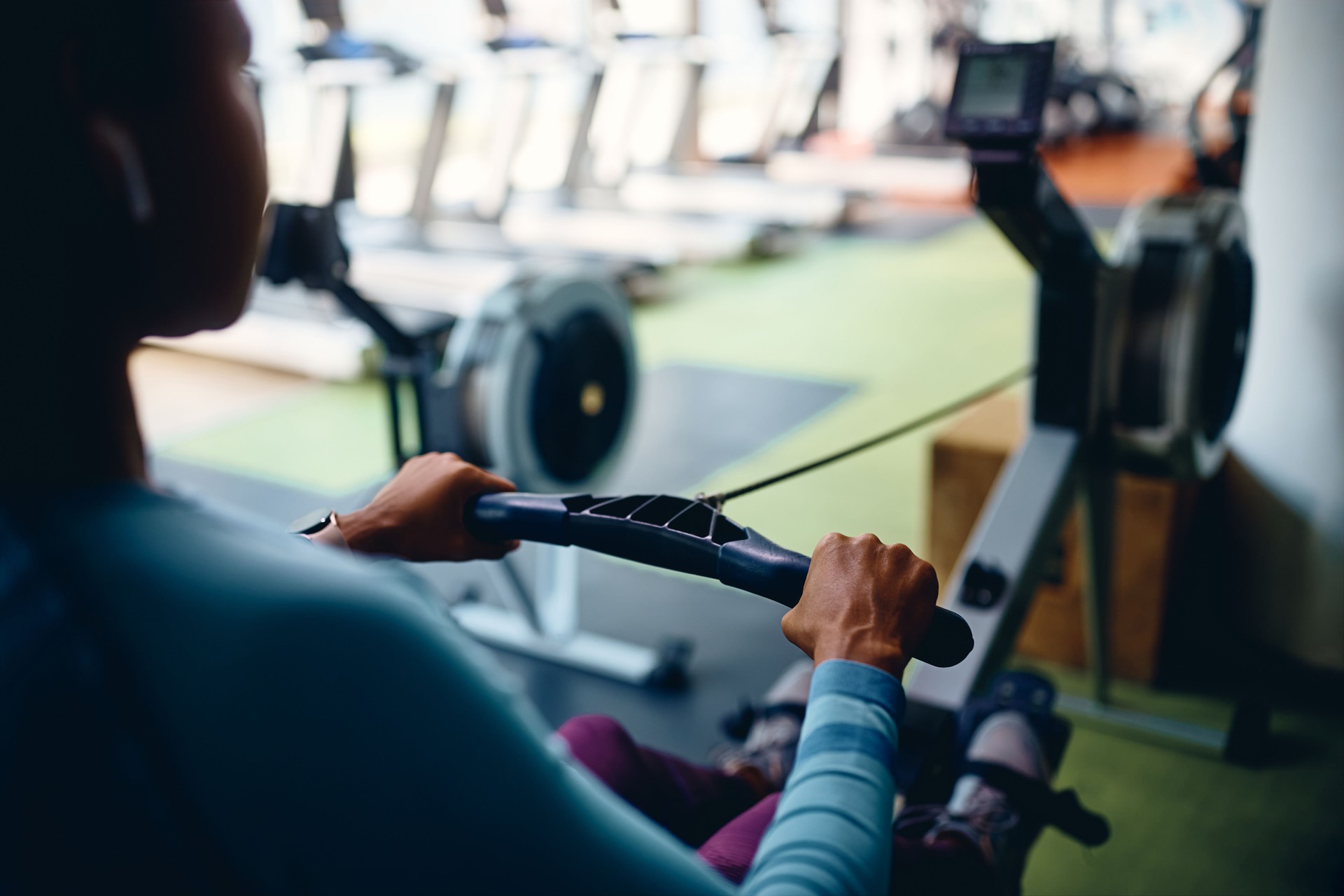 Close up of black sportswoman exercising on rowing machine in gym.