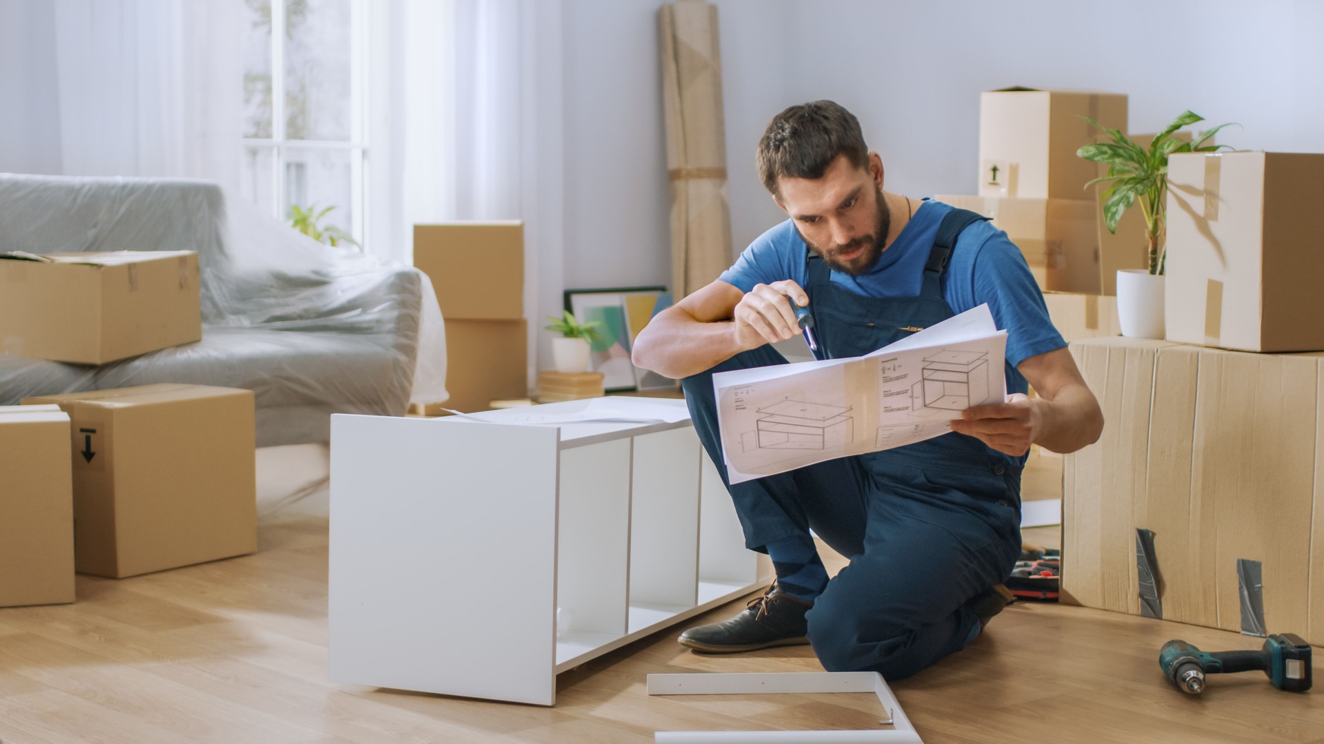 Successful Furniture Assembly Worker Reads Instructions to Assemble Shelf. Professional Handyman Doing Assembly Job Well, Helping People who Move into New House.